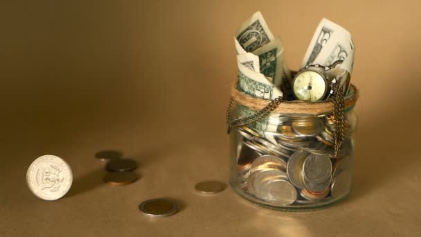 Économiser de l'argent pièce dans un bocal. Symbole d'investissement, concept de maintien de l'argent. Collecte de billets en espèces en étain de verre comme tirelire
 - Séquence, vidéo
