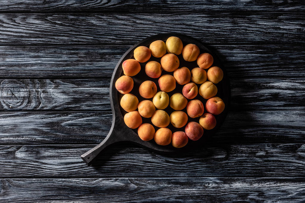 top view of pile of ripe apricots in tray on wooden table  - Valokuva, kuva
