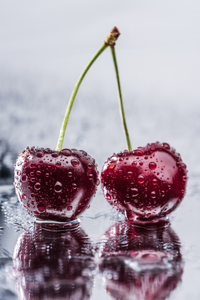close up view of red ripe cherries with water drops on wet surface  - Foto, Bild