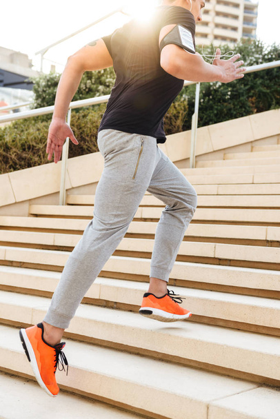 Cropped image of handsome young strong sports man outdoors running on steps. - Fotoğraf, Görsel