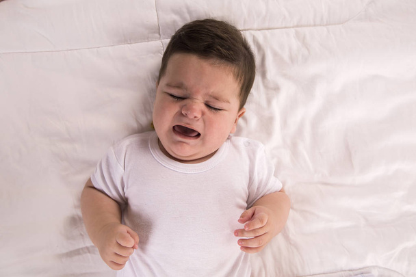 crying baby boy. New born child tired and hungry in bed. Children cry in bed - Foto, Imagen