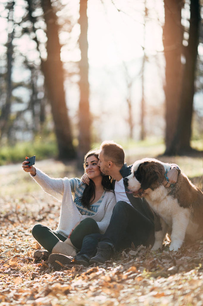 Casal jovem desfrutando da natureza ao ar livre, juntamente com seu adorável filhote de cachorro Saint Bernard. Pessoas e cães tema
. - Foto, Imagem