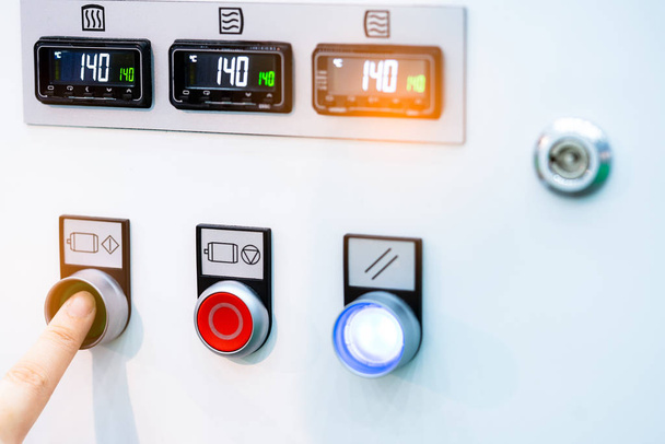 Рука инженера нажимает зеленую кнопку, чтобы открыть машину контроля температуры. Шкаф панели управления температурой содержит цифровой дисплей для датчика температуры. Контроль тепла на промышленных предприятиях
. - Фото, изображение