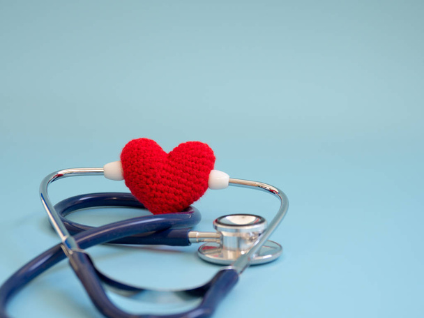 rotes Herz mit tiefblauem Stethoskop auf blauem Hintergrund. Konzept der Liebe und fürsorglichen Patienten durch das Herz. Kopierraum für Text und Inhalt - Foto, Bild