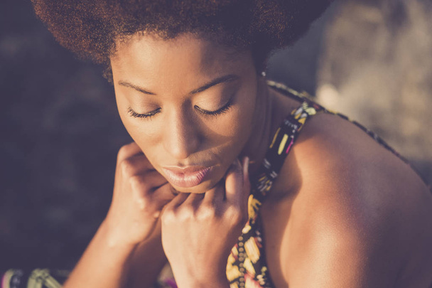 schöne schwarze afrikanische Rasse Modell mit geschlossenen Augen und die Hand auf dem Gesicht posieren unter dem Sonnenlicht. Schönheitskonzept für schwarze Haut und attraktive junge Dame - Foto, Bild