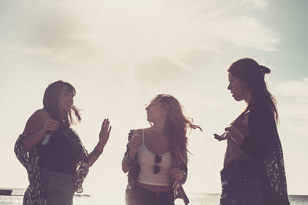 Relationship between three young beauty woman dancing on the beach during a vacation. Sunset time in Tenerife, flare effect and warm filter. - Photo, Image