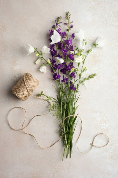 A beautiful bouquet of bellflowers and twine on a neutral background. Top view.  - Photo, Image