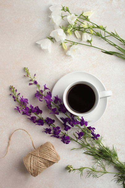 A beautiful bouquet of bells flowers and a cup of tea on a neutral background. Top view. - Fotó, kép