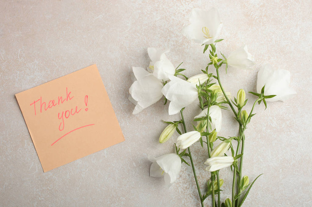 Un bellissimo bouquet di campanule bianche e una nota su sfondo neutro. Vista dall'alto, copia spazio
.  - Foto, immagini