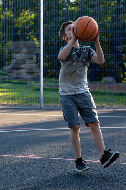 Pre-teen boy playing with a basketball in a park - Valokuva, kuva