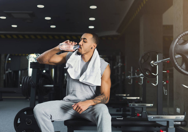 schwarzer Bodybuilder trinkt Wasser im Fitnessstudio - Foto, Bild