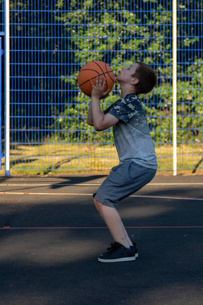 Pre-teen boy playing with a basketball in a park - Zdjęcie, obraz