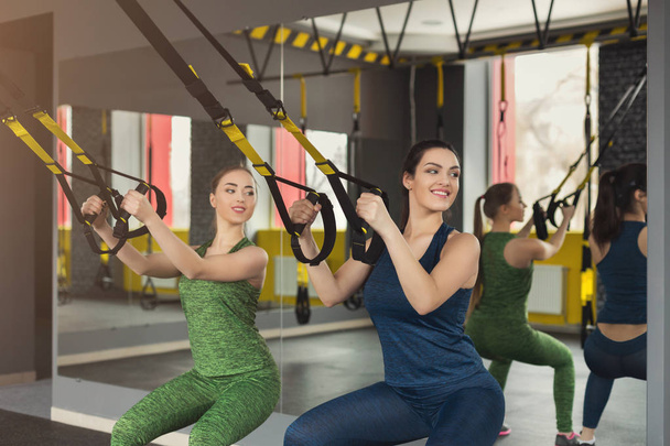 Mujeres realizando entrenamiento de suspensión en gimnasio
 - Foto, Imagen