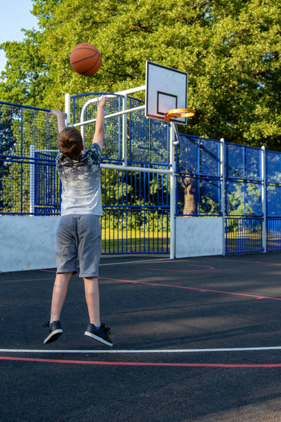 Pre-teen boy playing with a basketball in a park - 写真・画像