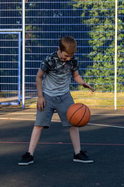 Pre-teen boy playing with a basketball in a park - Zdjęcie, obraz