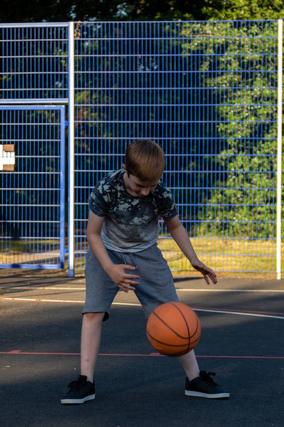 Pre-teen boy playing with a basketball in a park - Фото, зображення