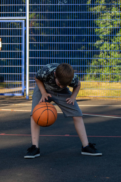 Pre-teen boy playing with a basketball in a park - Fotó, kép