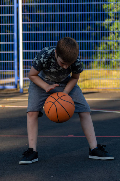 Pre-teen boy playing with a basketball in a park - Φωτογραφία, εικόνα