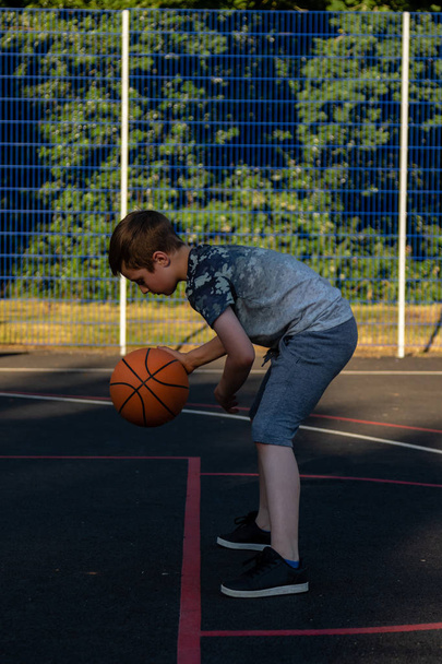 Pre-teen boy playing with a basketball in a park - Foto, Bild