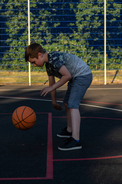 Pre-teen boy playing with a basketball in a park - Fotoğraf, Görsel