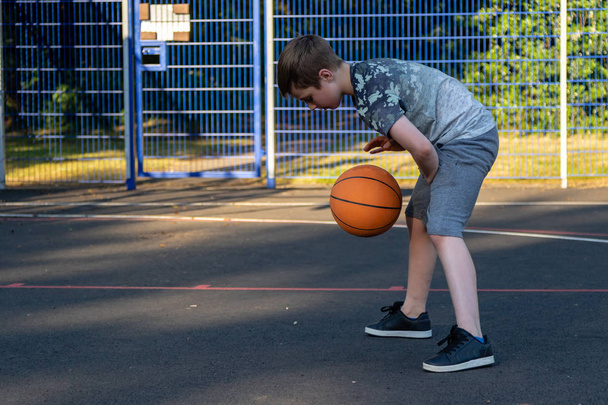 Pre-teen boy playing with a basketball in a park - Fotoğraf, Görsel