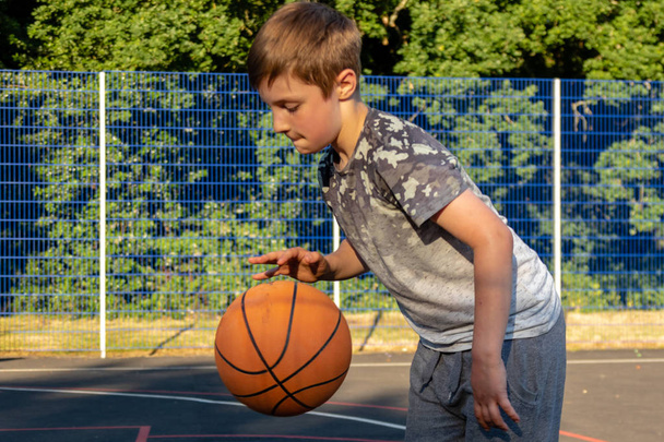 Pre-teen boy playing with a basketball in a park - Fotó, kép