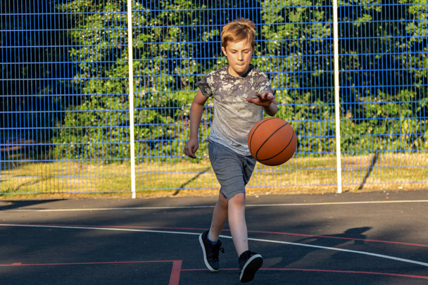 Pre-teen boy playing with a basketball in a park - 写真・画像