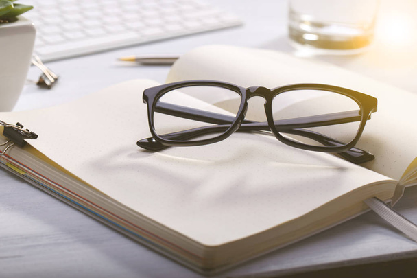 Open diary and glasses on modern desk, business or education concept, natural light - Foto, imagen
