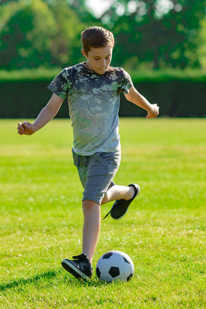 Pre-teen boy playing football in a park - Foto, afbeelding