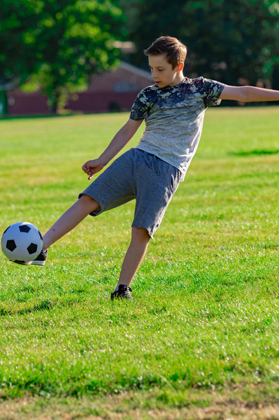 Pre-teen boy playing football in a park - Фото, зображення