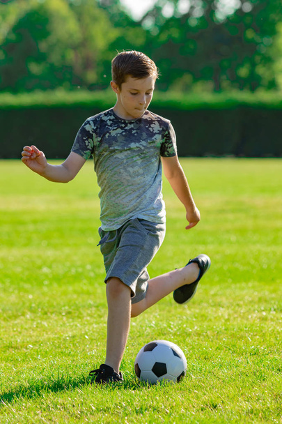 Pre-teen boy playing football in a park - Fotografie, Obrázek