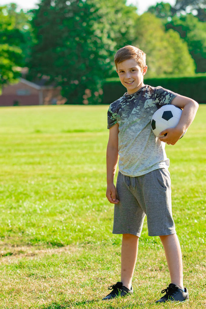 Pre-teen boy holding a football in a park - Foto, immagini