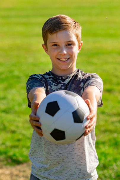 Pre-teen boy holding a football in a park - Photo, image