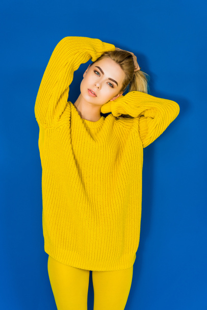 Attractive young girl in yellow sweater on blue background - Fotó, kép