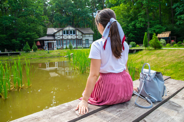 femme assise au quai se reposant près du lac. maison sur fond
 - Photo, image