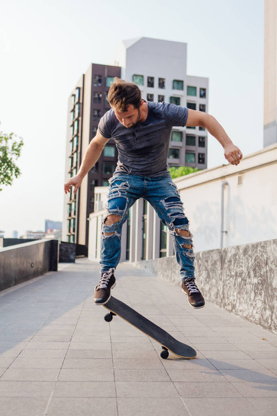 Skateboarder doing a skateboard trick ollie on the street of a city - Фото, изображение