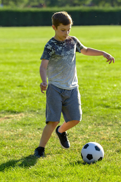 Pre-teen boy playing with a football in a park - Fotoğraf, Görsel