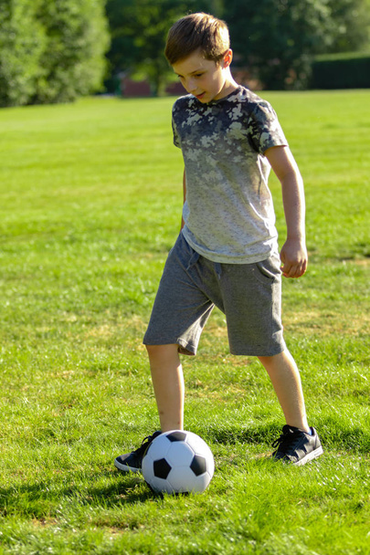 Pre-teen boy playing with a football in a park - Foto, Imagen