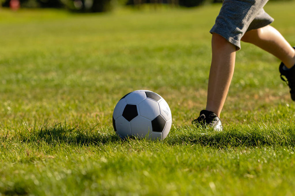Pre-teen boy playing with a football in a park - Photo, Image
