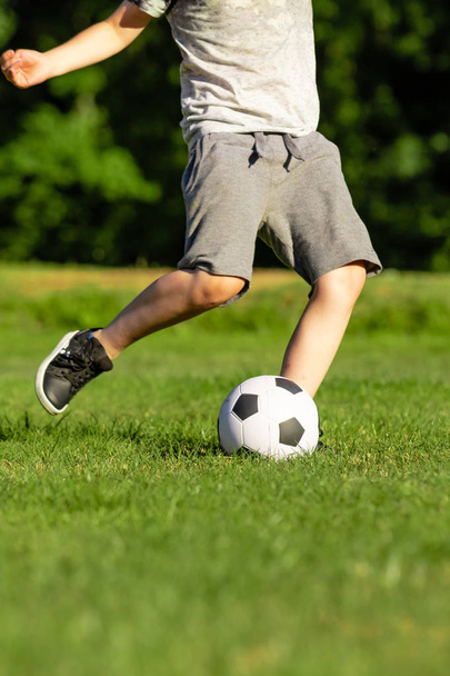 Pre-teen boy playing with a football in a park - 写真・画像