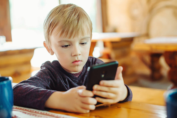 Kid hraní her na smartphonu. Chlapeček s smartphone pomocí Internetu. Návrh technologie. Předškolní chlapce, hraní her a sledování karikatury na mobilním telefonu - Fotografie, Obrázek