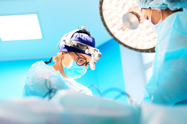Cirurgiões operando um paciente na sala de cirurgia
 - Foto, Imagem