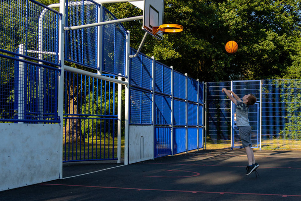 Pre-teen boy shooting basket ball in a park - Foto, Bild