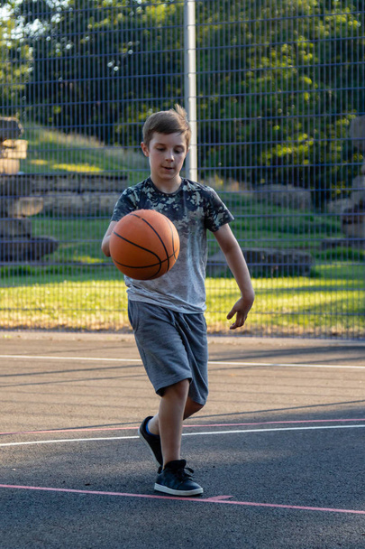 Pre-teen boy playing with a basketball in a park - Foto, Imagem