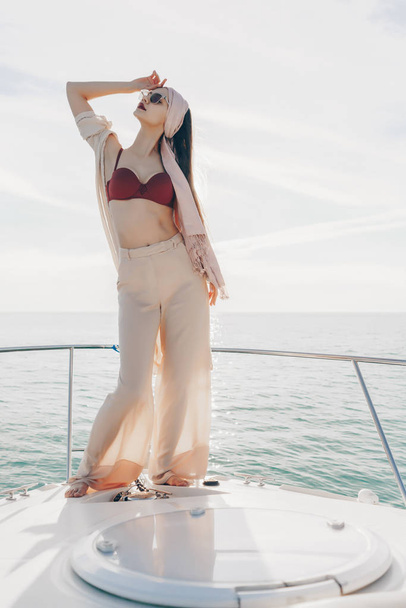 an attractive girl in stylish summer clothes posing on a yacht in the sun, enjoying sea voyage - Foto, Bild