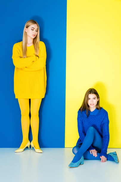 Elegant stylish women in contrasting clothes posing on blue and yellow background - Photo, Image