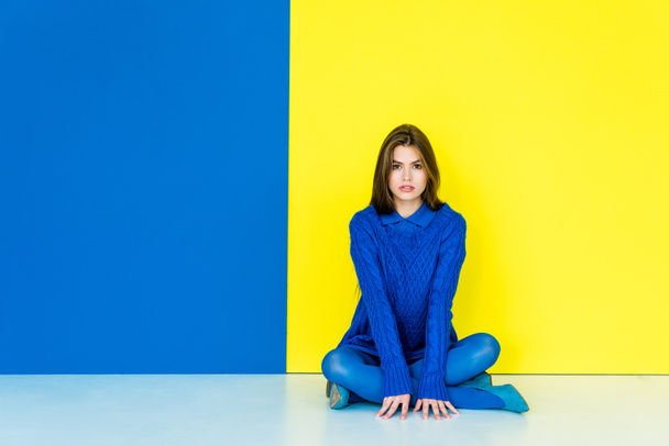 Beautiful brunette girl wearing blue clothes on blue and yellow background - Zdjęcie, obraz