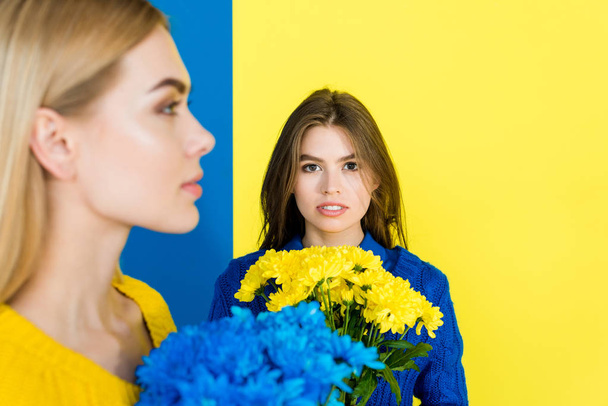 Elegant stylish women with blue and yellow chrysanthemums isolated on blue and yellow background - Φωτογραφία, εικόνα