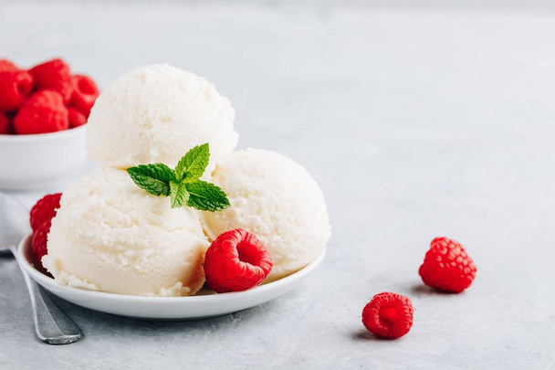 Vanilla ice cream with fresh raspberries and mint leaves in white bowl - Photo, Image