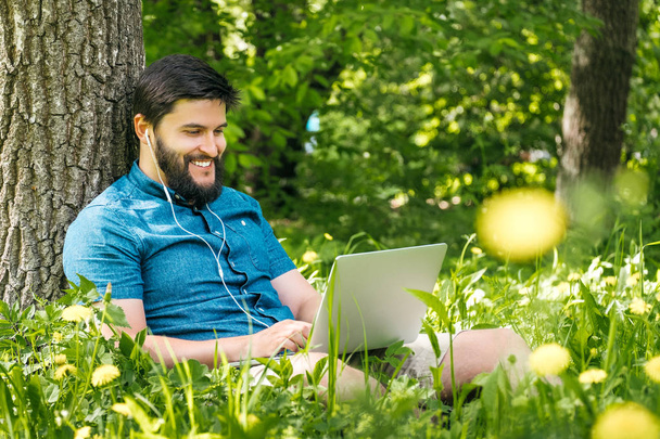 Young businessman or student in casual dress using laptop in the park. Outdoor office concept - Фото, зображення